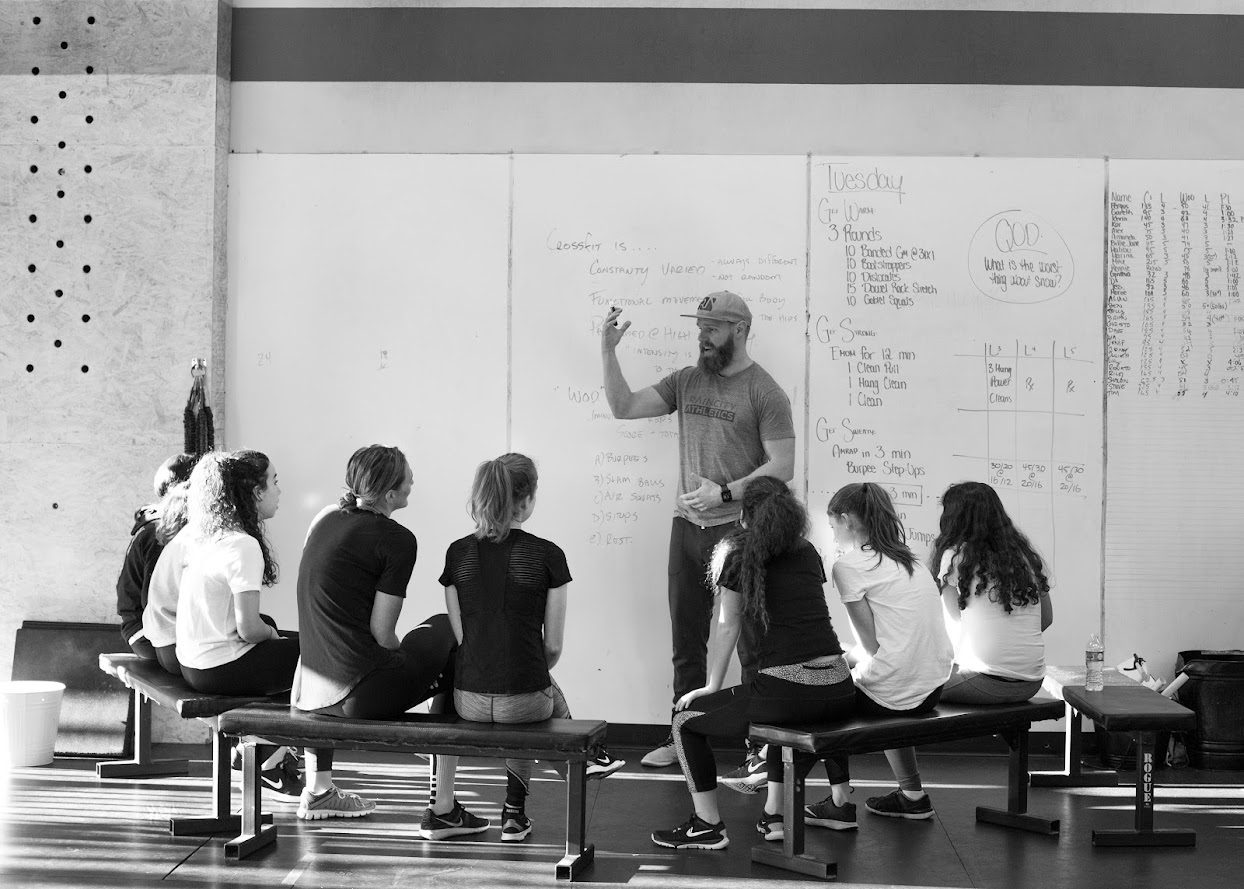 Coach Thor teaching a group of students at a whiteboard